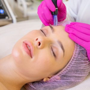 Woman in a spa salon on cosmetic procedures for facial care. Beautician makes skin care procedure on a  face.  Cosmetologist making a woman a therapeutic laser processing on a face.